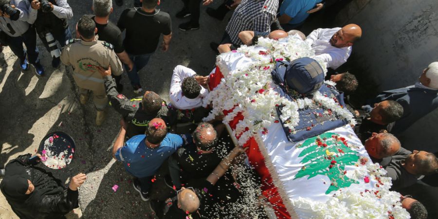 ARCHIV - Eine Frau wirft Reis und Rosenblätter auf den Sarg der libanesischen Journalistin Amal Khalil, die am Mittwoch bei einem israelischen Luftangriff getötet wurde, während ihre...