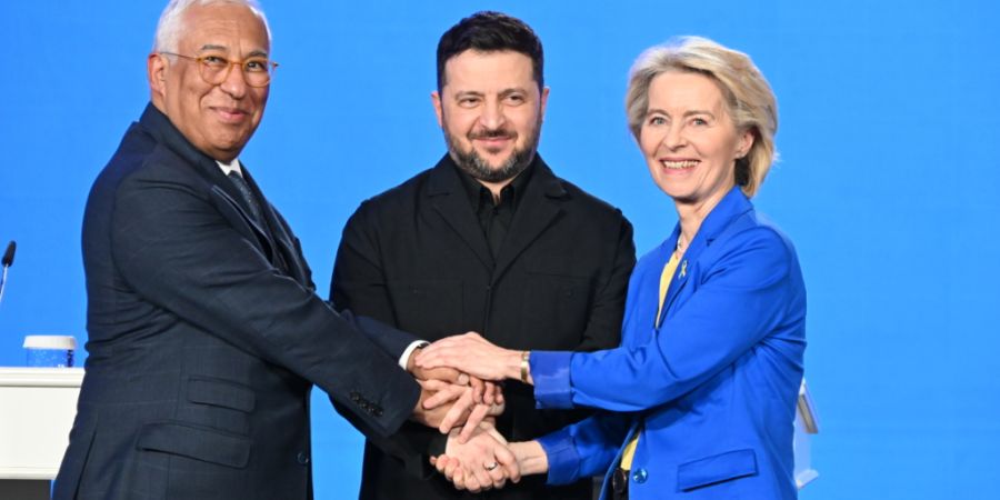 ARCHIV - Der ukrainische Präsident Wolodymyr Selenskyj, EU-Kommissionspräsidentin Ursula von der Leyen und EU-Ratspräsident António Costa geben sich nach einer Pressekonferenz die H...