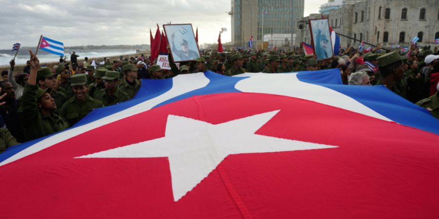 Menschen tragen eine kubanische Flagge während einer von der Regierung organisierten Kundgebung in Havanna. Foto: Ramon Espinosa/AP/dpa