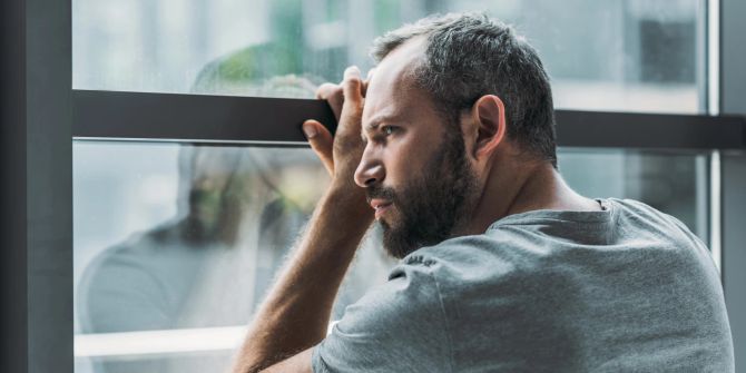 mann, schaut gedankenverloren aus dem fenster