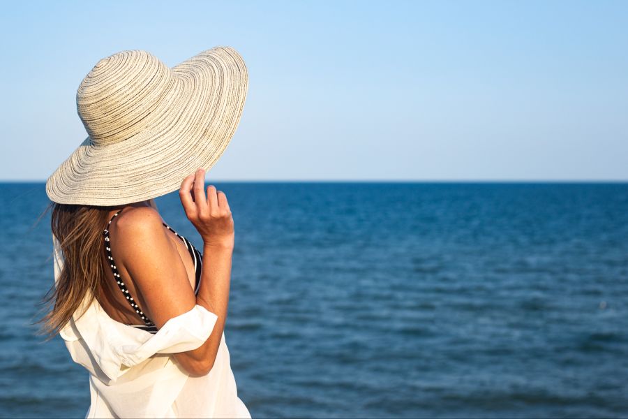 Frau mit Hut am Meer