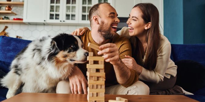 Positives Paar spielt Holzklötzchen-Spiel mit Border Collie.