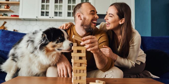 Die intelligentesten Hunde der Welt verstehen bis zu 250 Wörtern! Positives Paar spielt Holzklötzchen-Spiel mit Border Collie.