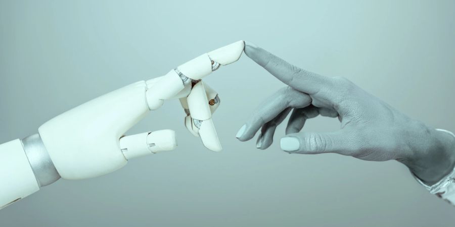 Eine robotergesteuerte Hand berührt mit dem Zeigefinger einen menschlichen Zeigefinger