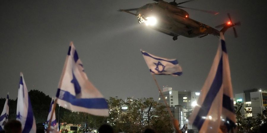 Menschen schwenken in Petach Tikwa israelische Fahnen, während ein Hubschrauber mit Geiseln, die von der Hamas aus dem Gazastreifen freigelassen wurden, landet (Archivbild).