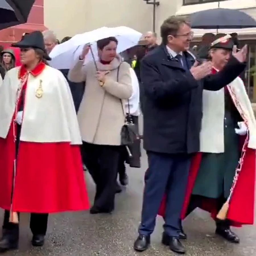 Bundesrat Albert Rösti grüsst die Untertanen der Stadtmusik Liestal. Im Hintergrund macht die Baselländler Regierungspräsidentin Monica Gschwind den Schirm zu.