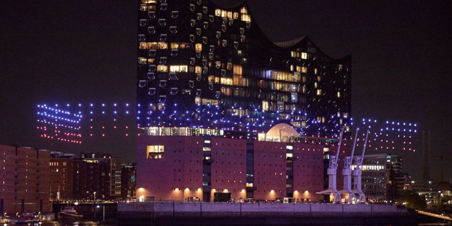Beleuchtete Drohnen fliegen über der Elbe vor der Elbphilharmonie.