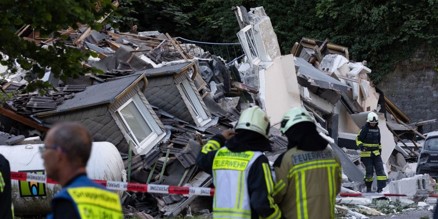 Feuerwehrleute stehen vor dem eingestürzten Haus in Hemer.