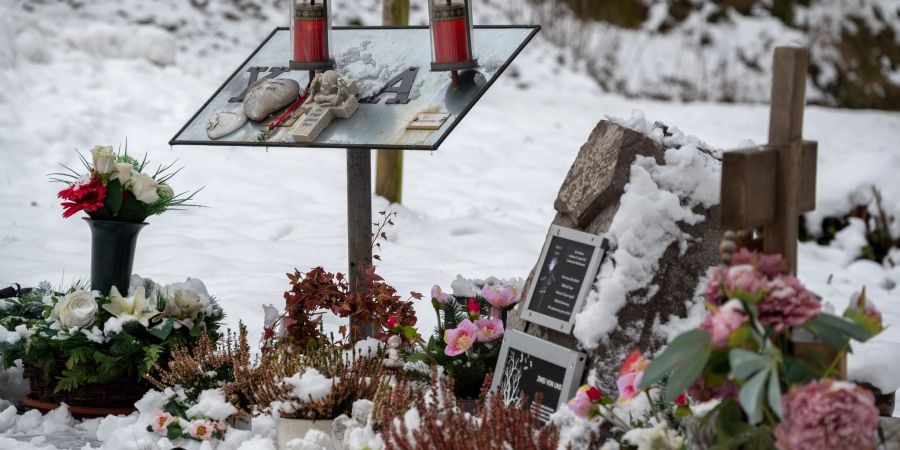 Ein Gedenkstein, eine Gedenktafel, Engelfiguren und Blumen erinnern auf einem Parkplatz bei Kusel an zwei Polizisten, die vor einem Jahr im Dienst getötet wurden.