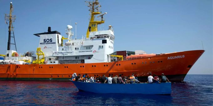 Flüchtlinge sitzen vor der libyschen Küste in einem Holzboot. Flüchtlinge sitzen vor der libyschen Küste in einem Holzboot.
