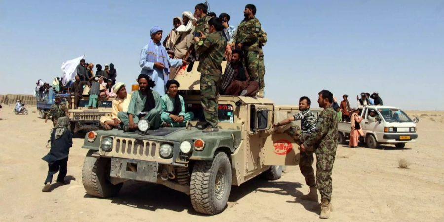 Taliban-Mitglieder posieren mit afghanischen Soldaten auf einem Auto.