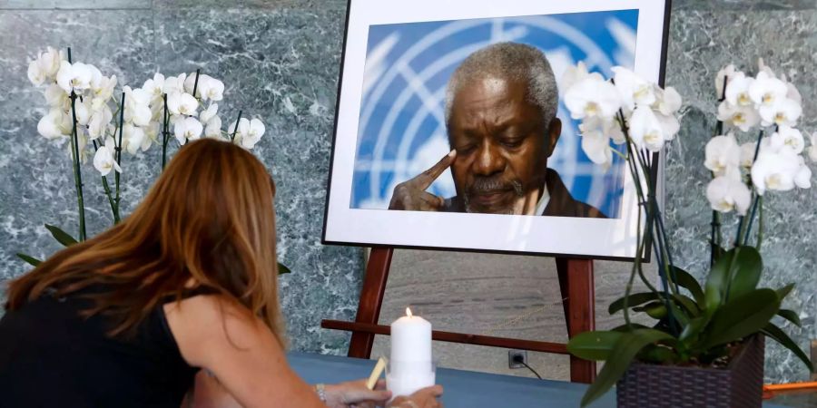 Eine UNO-Mitarbeiterin stellt eine Kerze vor ein Porträt des ehemaligen UNO-Generalsekretärs Kofi Annan.