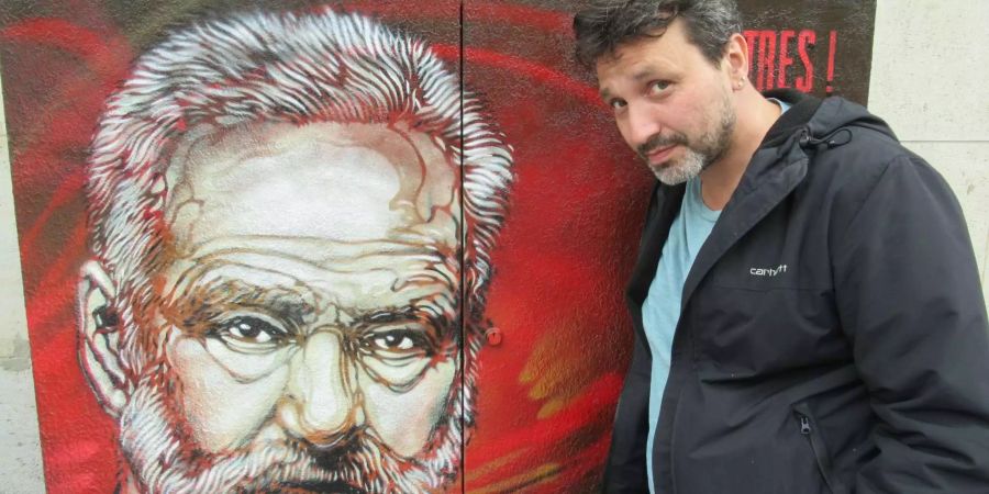 Christian Guemy, französischer Streetart-Künstler und bekannt unter dem Pseudonym C215, steht neben einem von ihm angefertigten Portrait von Victor Hugo.