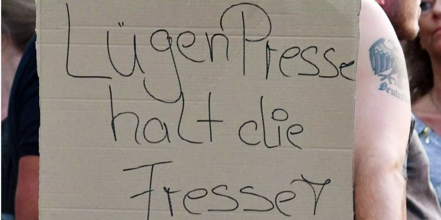 Ein Teilnehmer einer Kundgebung rechter Gruppen hält ein Plakat mit der Aufschrift «LügenPresse halt die Fresse!».