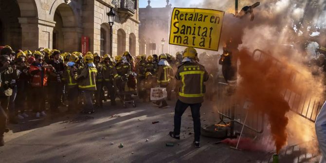 Rauch tritt aus einer Rauchgranate neben demonstrierenden Feuerwehrleute aus.