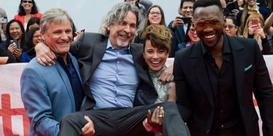 Director Peter Farrelly, wird von den Schauspielerin Viggo Mortensen, Linda Cardellini und Mahershala Ali in die Höhe gehoben.