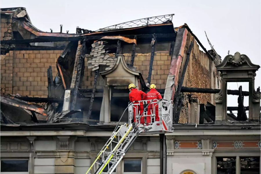 Feuerwehrleute begutachten ein ausgebranntes Gebäude am Bahnhofsplatz in der Nähe des Hauptbahnhofs.