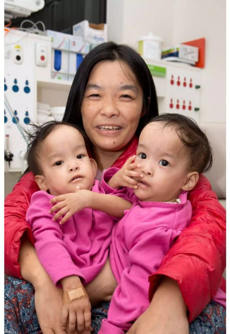 Die vierzehn Monate alten siamesischen Zwillinge Nima (rechts) und Dawa (links) sitzen mit ihrer Mutter Bhumchu Zangmo im Royal Children's Hospital in Melbourne.