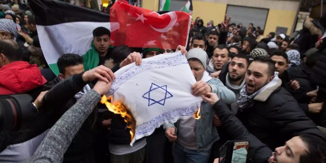 Teilnehmer einer Demonstration verbrennen eine selbstgemalte Fahne mit einem Davidstern im Stadtteil Neukölln.