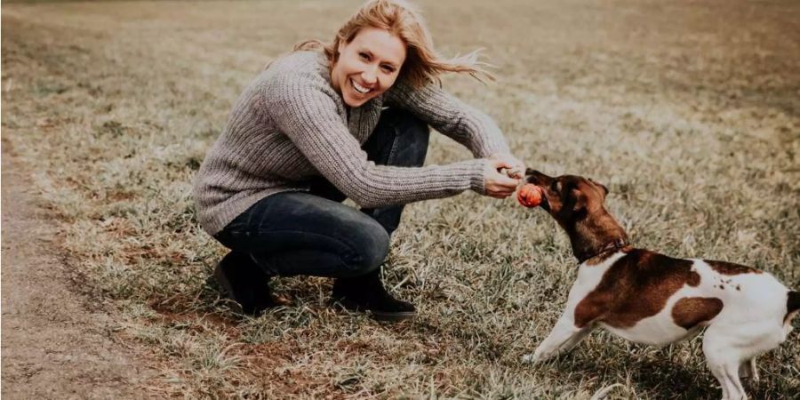 Sara Bachmann und ihre Jack-Russell-Dame Aria spielen auf einer Wiese.