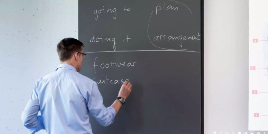 Ein Lehrer schreibt Englischvokabeln an die Wandtafel.