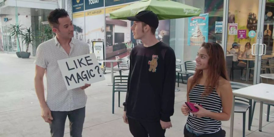 Justin Willman spricht für einen Zaubertrick ein Paar auf der Strasse an.