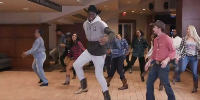 Clint Capela lernt mit einem den Line-Dance mit einem Lehrer. Clint Capela tanzt mit einem Line-Dance-Lehrer und einer Gruppe im Hintergrund.