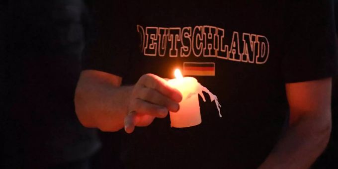 Ein Teilnehmer einer Kundgebung für einen verstorbenen 22-Jährigen legt auf einem Spielplatz eine Kerze ab. Ein Teilnehmer einer Kundgebung für einen verstorbenen 22-Jährigen legt auf einem Spielplatz eine Kerze ab.
