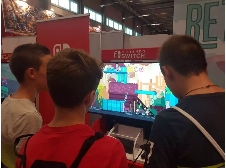 Einige Jugendliche Besucher des HeroFests Spielen Retimed am Nintendo Stand.