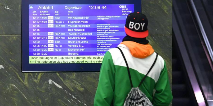 Ein Mann steht vor einer Anzeigetafel am Westbahnhof in Wien, die über den eingestellten Zugverkehr informiert.