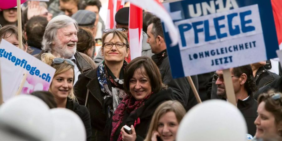 Frauen und Maenner verschiedener Organisationen bei einer Demonstration für Lohngleichheit.