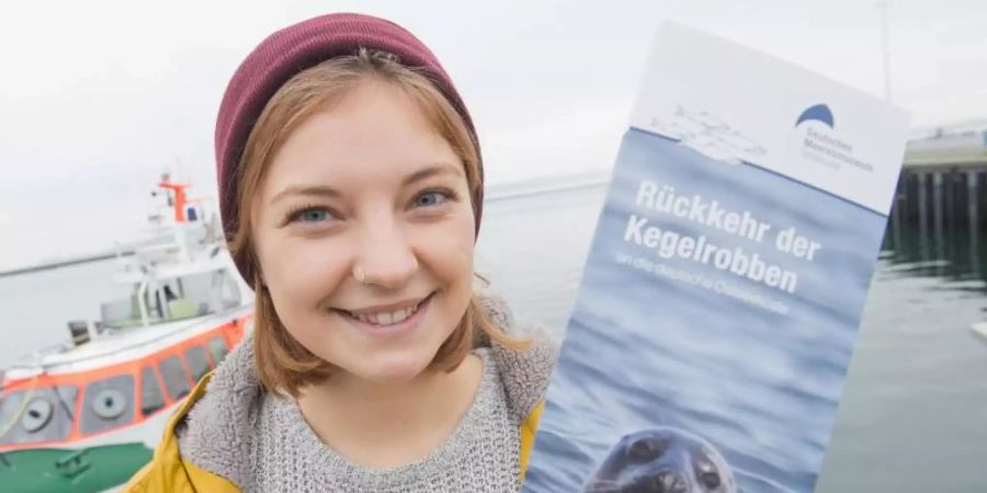 Linda Westphal, Meeresbiologin am Deutschen Meeresmuseum,zeigt eine Broschüre zur Rückkehr der Kegelrobben in der Ostsee. Foto: Stefan Sauer/dpa