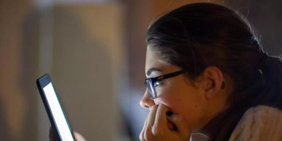 Eine junge Frau liest ein E-Book auf einem digitalen Lesegerät. Foto: Jens Büttner/zb/dpa