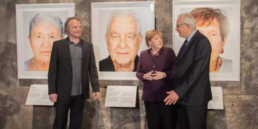 Der Künstler Martin Schoeller (l), der Holocaust-Überlebende Naftali Fürst und Bundeskanzlerin Angela Merkel (CDU) bei der Eröffnung der Ausstellung «Survivors - Faces of Life after the Holocaust» in Essen. Foto: Rolf Vennenbernd/dpa