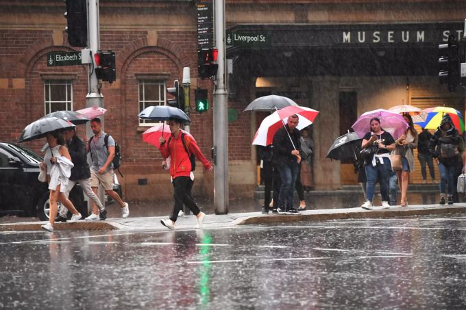 Passanten gehen in Sydney mit Schirmen durch den Regen. Regen in Sydney
