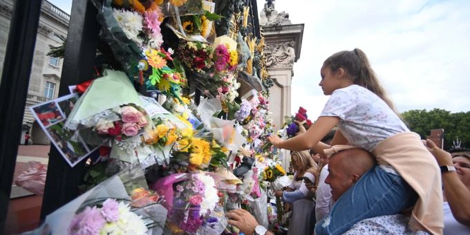 Ein Mädchen hängt nach dem Tod von Queen Elizabeth Blumen an das Gitter vor dem Buckingham-Palast. Queen Elizabeth