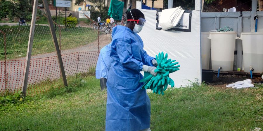 Ein Mitarbeiter in medizinischer Schutzkleidung trägt Schutzhandschuhe in einem Krankenhaus, in dem ein Ebola-Opfer isoliert wurde.