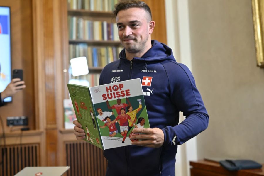 Xherdan Shaqiri hält das Kinder-Fussballbuch «Hopp Schwiiz» in der Hand.