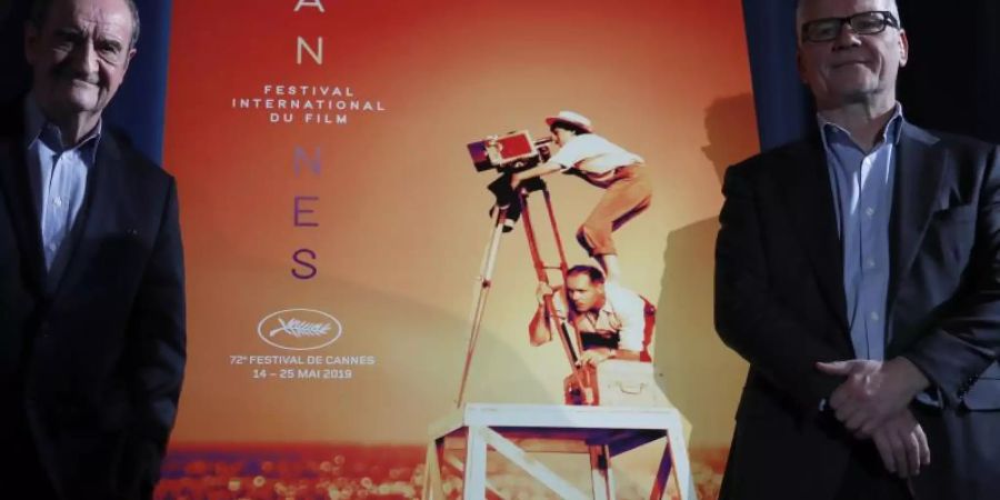 Festivaldirektor Thierry Frémaux (r) und Festivalpräsident Pierre Lescure vor dem offiziellen Cannes-Plakat, das die verstorbene Regisseurin Agnès Varda zeigt. Foto: Francois Mori/AP