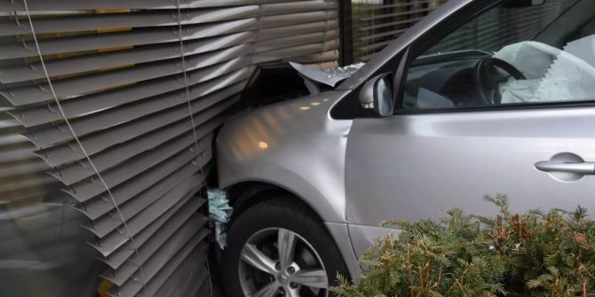 Silbernes Auto an Haus geprallt; Vorderfront eingedrückt