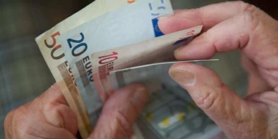 Eine ältere Frau zählt Geld. Foto: Marijan Murat/Illustration