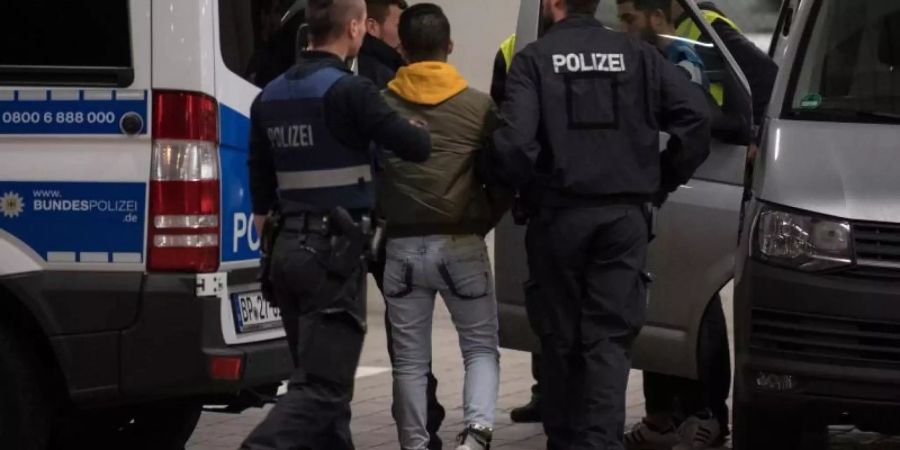 Polizisten bringen einen jungen Mann aus Afghanistan zur Abschiebung zum Frankfurter Flughafen. Foto: Boris Roessler