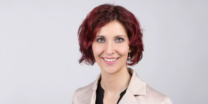 Frau mit roten Haaren in einem hellen Anzug