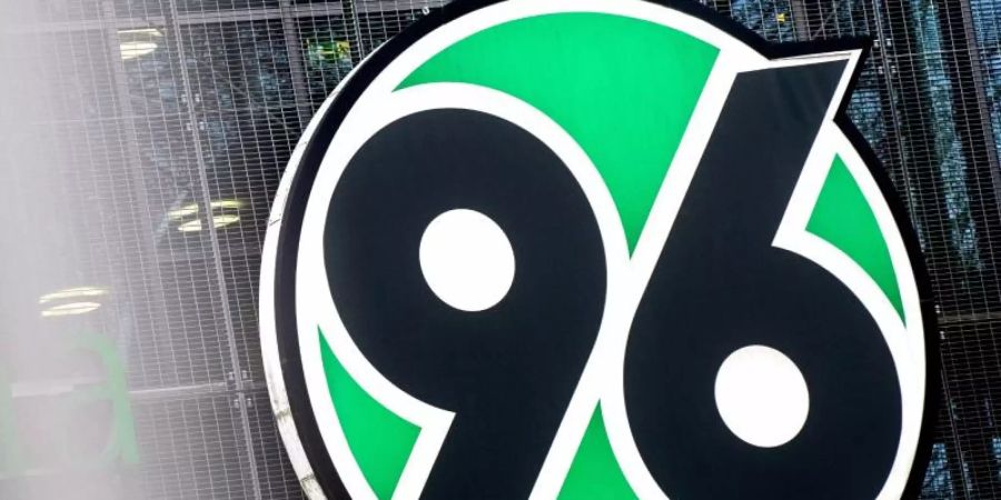Das Logo von Fussball-Bundesligist Hannover 96 hängt an der HDI-Arena. Foto: Hauke-Christian Dittrich/dpa