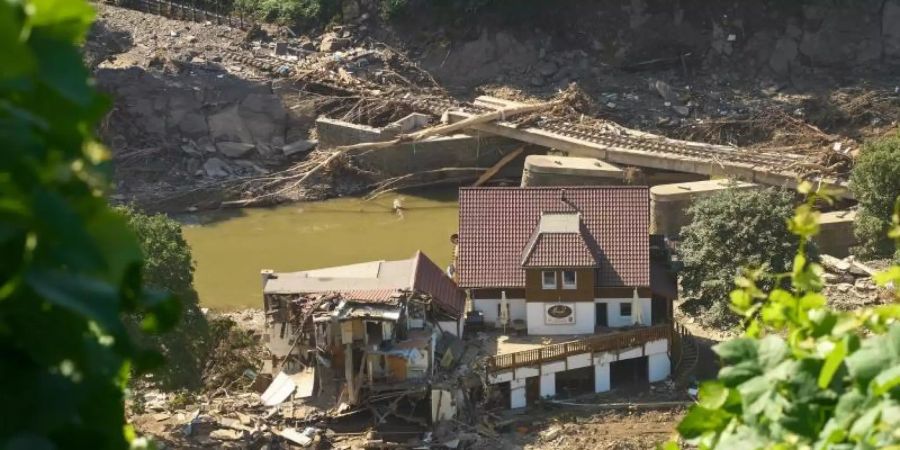Ein Haus in Marienthal ist nach dem Hochwasser vollkommen aufgerissen, dahinter ist eine zerstörte Brücke zu sehen. Foto: Thomas Frey/dpa