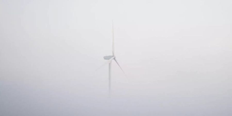 Ein Windrad ragt bei Hannover aus dem morgendlichen Nebel. Foto: Julian Stratenschulte/dpa