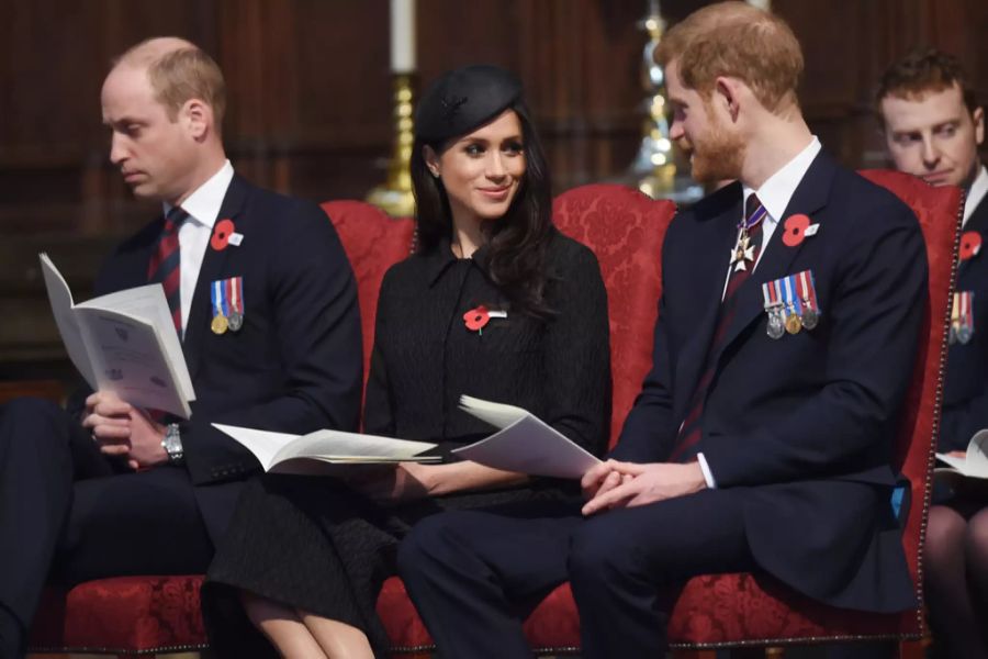 Prinz William, Meghan Markle und Prinz Harry sitzen nebeneinander.