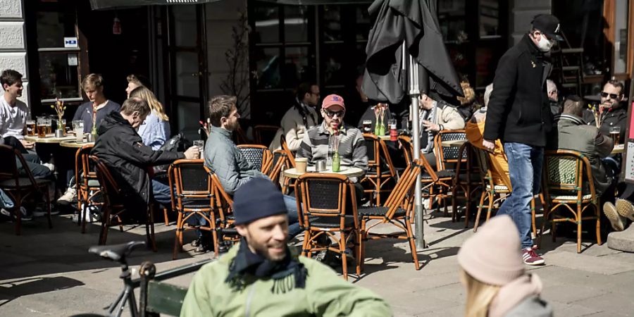 Menschen sitzen im belebten Aussenbereich eines Cafés in Kopenhagen.