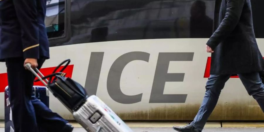 Fahrgäste gehen mit ihrem Gepäck an einem ICE-Zug vorbei. Der Zug schlägt das Auto und das Flugzeug weiter beim klimafreundlichen Reisen. Foto: Christoph Schmidt/dpa