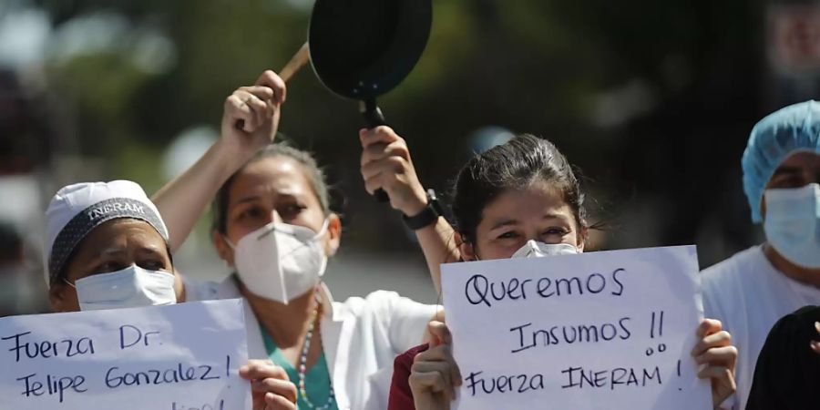 «Wir wollen Arbeitsmaterial», «Halten Sie durch, Dr. Felipe Gonzalez», steht auf den Plakaten von Mitarbeitern eines Krankenhauses, die an einem Protest teilnehmen. Foto: Jorge Saenz/AP/dpa